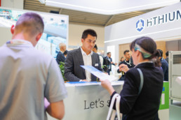 Asian man standing behind the counter of an exhibition stand